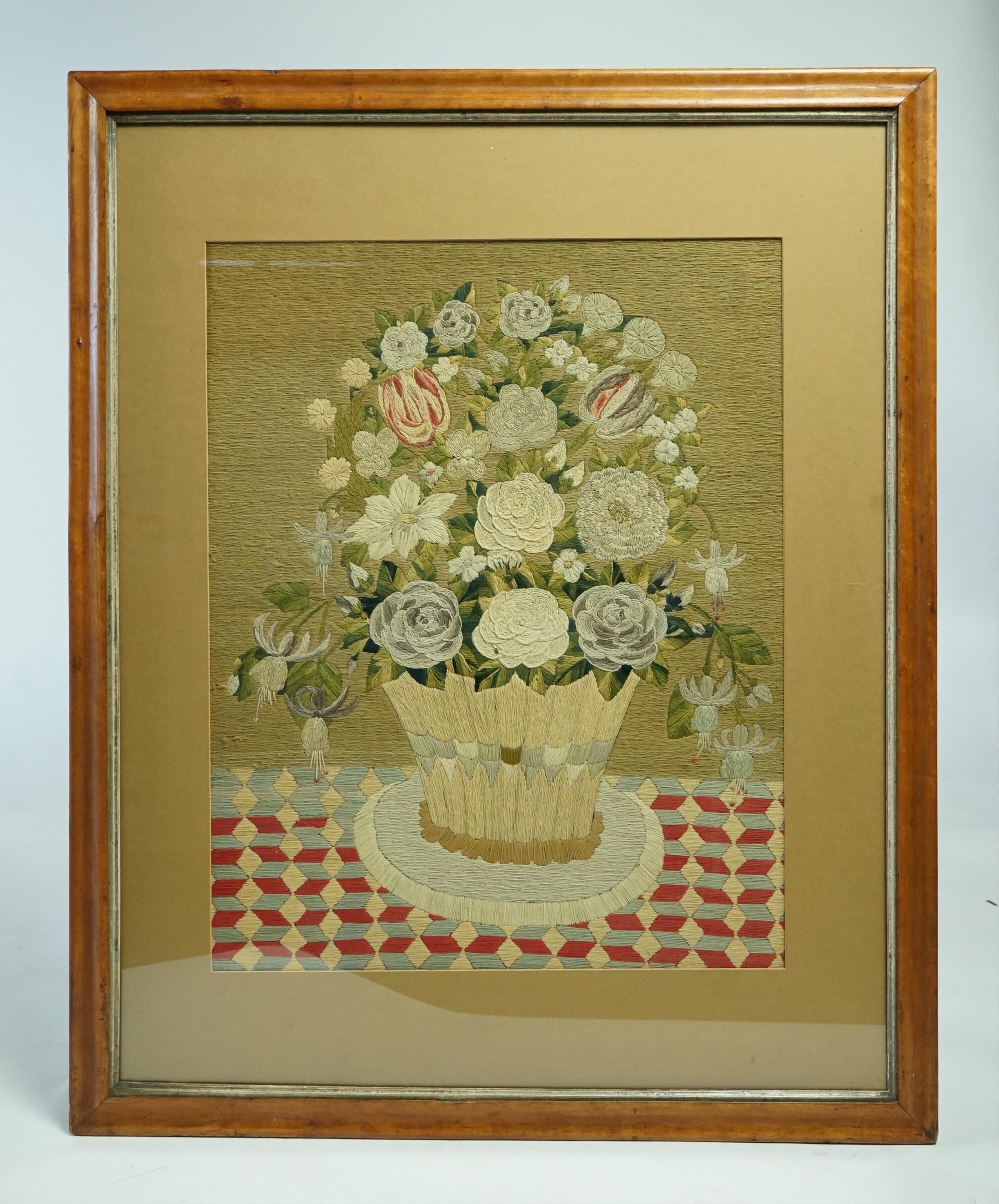 A large maple framed 19th century wool worked still life embroidery of a vase flowers on a check patterned cloth, worked in stem stitch and then over stitched in places to give depth. 48cm wide x 60.5cm high. Condition -